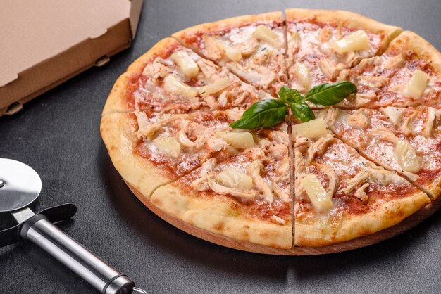 Savoureuse pizza au four avec tomates, fromage et ananas sur un fond de béton foncé