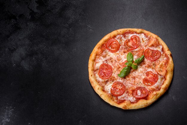 Savoureuse pizza au four avec tomates, fromage et basilic sur une table sombre