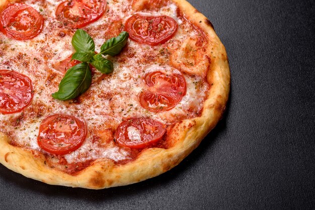 Savoureuse pizza au four avec tomates, fromage et basilic sur une table sombre