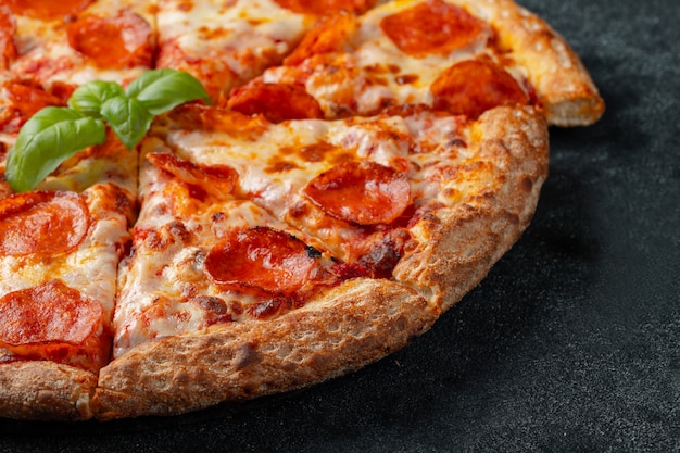 Savoureuse pizza au pepperoni sur un fond de béton noir.