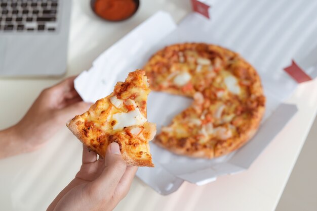 Savoureuse pizza sur le bureau avec coca et ordinateur portable, restauration rapide