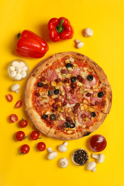 Savoureuse pizza et ingrédients sur jaune