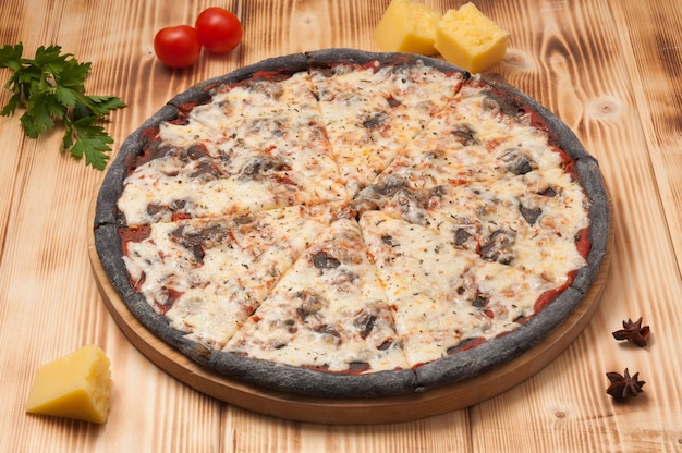 Savoureuse pizza Margarita sur pâte noire sur une planche de bois
