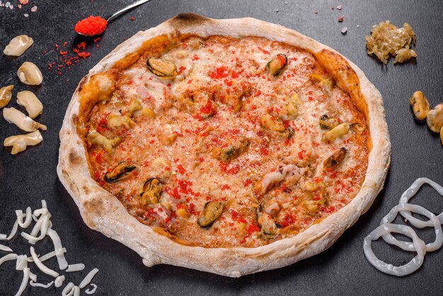 Savoureuse pizza en tranches avec fruits de mer et tomate sur fond noir. Cuisine méditerranéenne