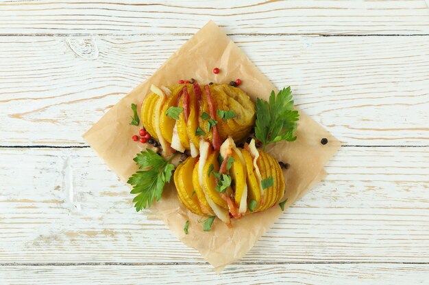 Savoureuse pomme de terre au four sur une table en bois blanche.