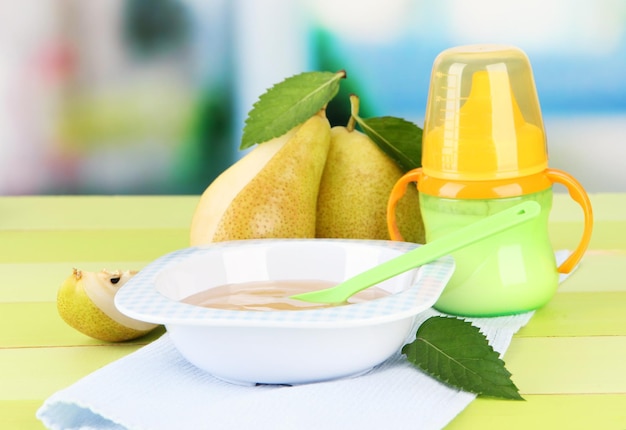 Savoureuse purée de fruits pour bébé et biberon sur table en bois