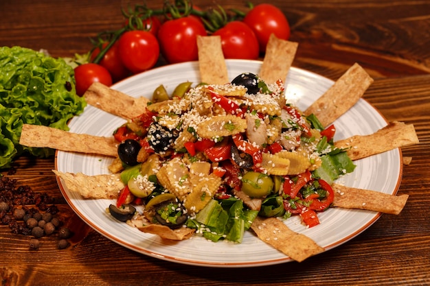 Savoureuse salade en assiette avec olives, petits grains de maïs marinés, viande, poivre et autres ingrédients.