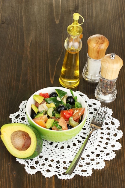 Savoureuse salade d'avocat dans un bol entouré d'épices sur une table en bois libre