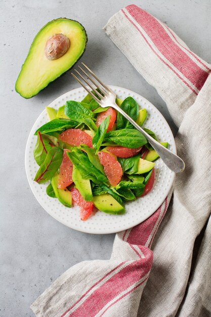 Savoureuse salade d'épinards, de blettes, d'avocat et de pamplemousse avec de l'huile d'olive sur une vieille surface gris béton