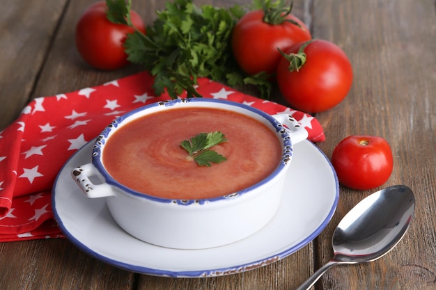 Savoureuse soupe aux tomates et légumes sur table en bois