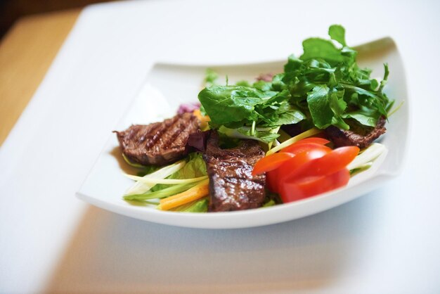 savoureuse viande de barbecue, steak de boeuf juteux avec fromage grillé et salade au restaurant