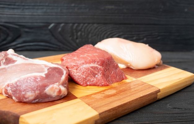 Savoureuse viande de veau crue ou de boeuf sur une planche à découper en bois