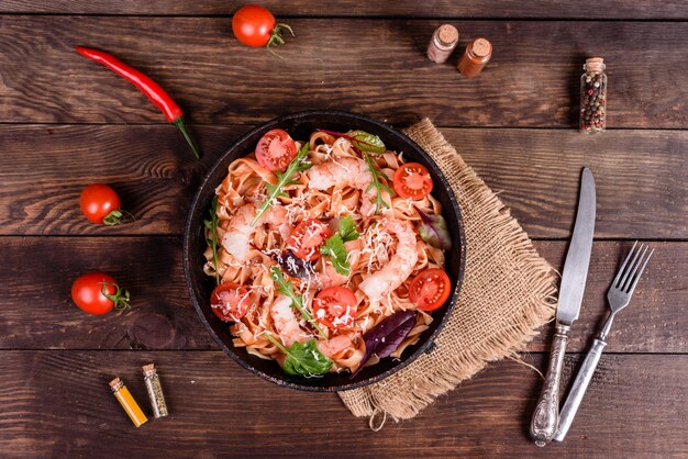 Savoureuses pâtes aux crevettes et à la tomate sur une poêle à frire