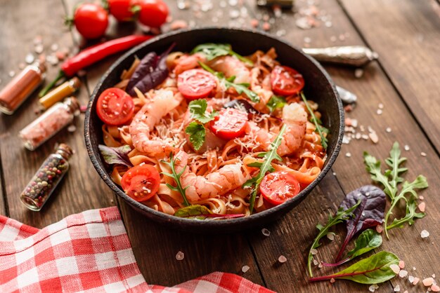 Savoureuses pâtes aux crevettes et à la tomate sur une poêle à frire