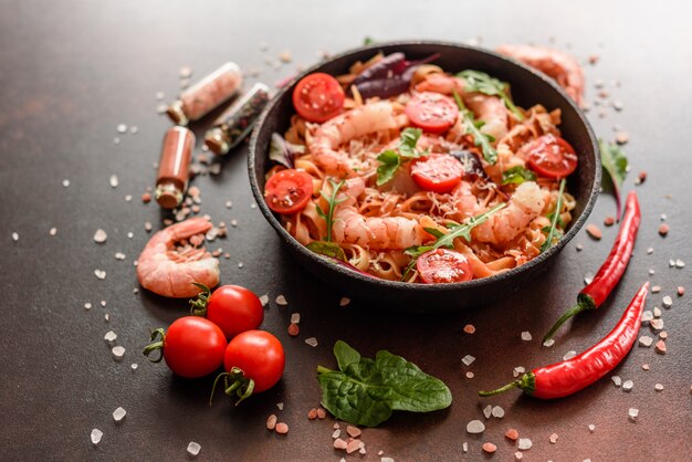 Savoureuses pâtes aux crevettes et à la tomate sur une poêle à frire