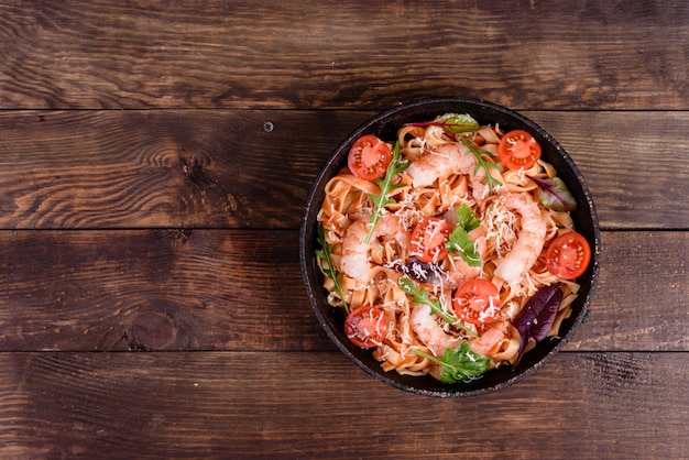 Savoureuses pâtes aux crevettes et à la tomate sur une poêle à frire