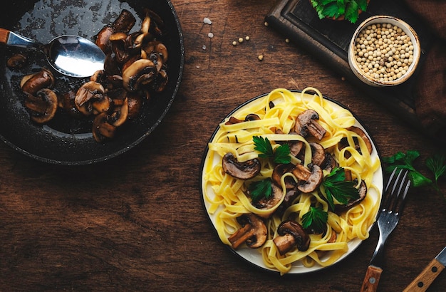 Savoureuses pâtes fettuccine aux champignons servies sur une assiette avec des légumes verts et des épices sur la vue de dessus de fond de table de cuisine en bois rustique Cuisine végétarienne saine et manger concept de cuisine italienne