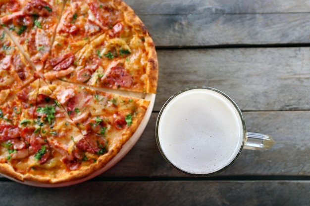 De savoureuses pizzas et un verre de bière sont sur une table en bois se bouchent