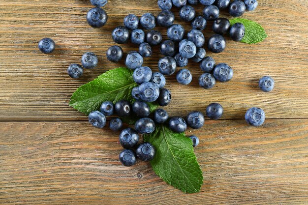 De savoureux bleuets mûrs avec des feuilles vertes sur une table en bois se bouchent