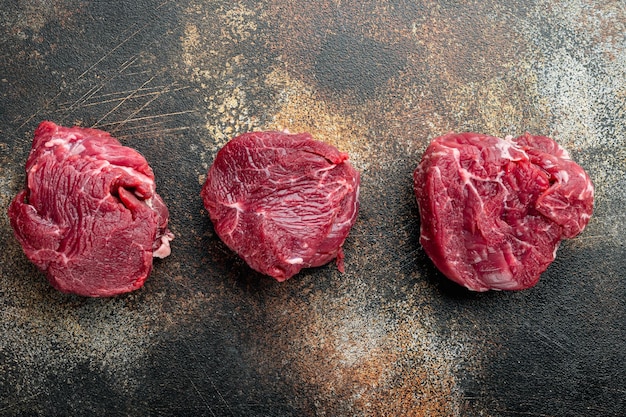 Savoureux cru de veau ou de viande de boeuf haut de gamme situé sur un vieux fond rustique foncé Filet mignon coupé vue de dessus mise à plat avec espace de copie pour le texte