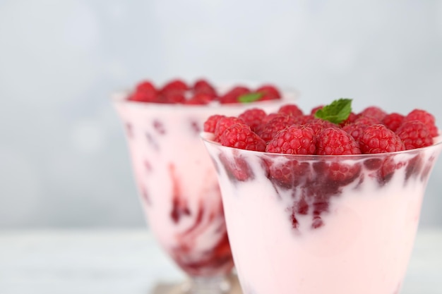 Savoureux dessert aux framboises avec des baies sur une table en bois sur fond clair