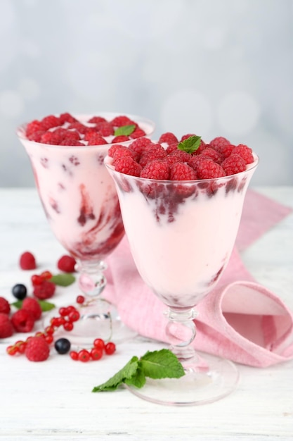 Savoureux dessert aux framboises avec des baies sur une table en bois sur fond clair