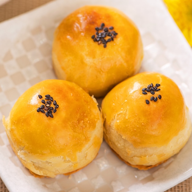 Savoureux gâteau de lune au jaune d'oeuf cuit au four pour la fête de la mi-automne sur fond de table en bois clair. Concept de cuisine festive chinoise, gros plan, espace de copie.