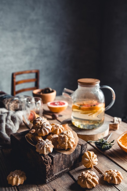 De savoureux gâteaux avec du thé chaud avec des tranches de pamplemousse frais sur tablette en bois