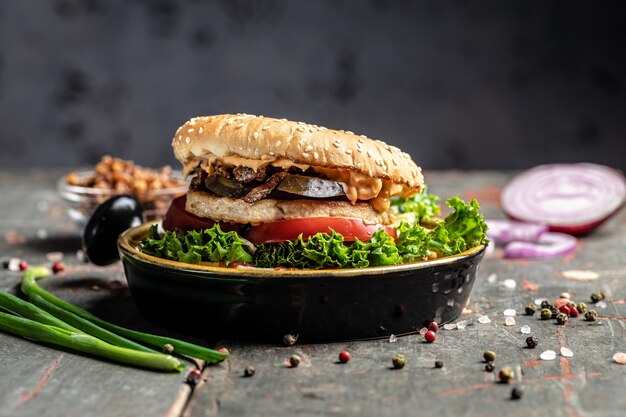 Savoureux hamburger maison grillé avec du poulet, des cornichons et des oignons frits sur une table en bois. bannière, menu, lieu de recette pour le texte