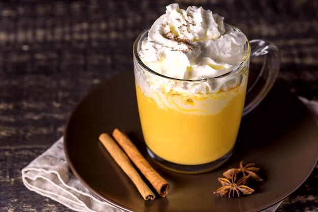 Savoureux latte de citrouille aux épices crème fouettée sur le dessus sur un fond en bois foncé Boisson chaude d'automne