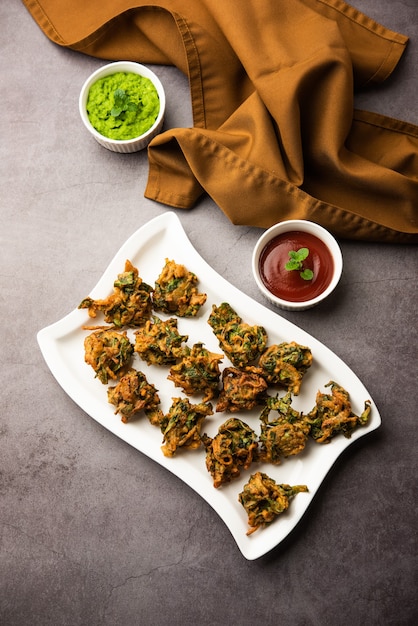 Savoureux Palak pakoda ou pakora fait maison, connu sous le nom de Firtters aux épinards, servi avec du ketchup. Collation préférée à l'heure du thé en Inde