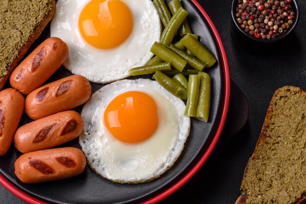 Savoureux petit-déjeuner anglais composé d'oeufs au plat, de haricots, d'asperges, de saucisses aux épices et d'herbes