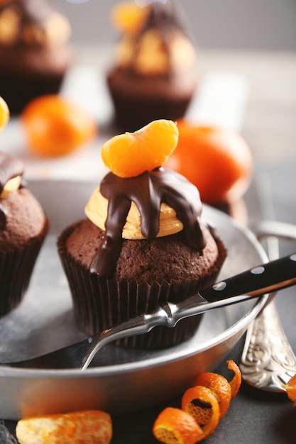 Photo de savoureux petits gâteaux avec une tranche de mandarine et de chocolat dans une casserole se bouchent