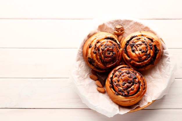 De savoureux petits pains à la cannelle chauds et du chocolat sur un fond en bois blanc. Rouleaux de cannelle sucrés frais faits maison. Place pour le texte. Vue de dessus.