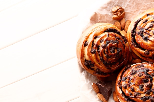 De savoureux petits pains à la cannelle chauds et du chocolat sur un fond en bois blanc. Rouleaux de cannelle sucrés frais faits maison. Place pour le texte. Vue de dessus.