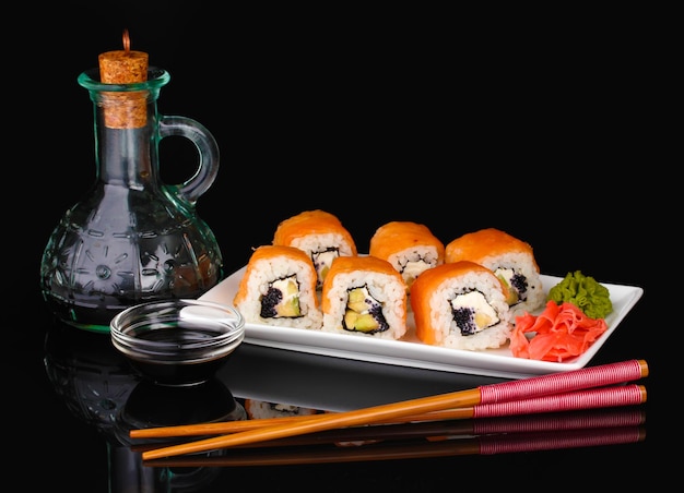 Savoureux petits pains servis sur une assiette blanche avec des baguettes et de la sauce soja isolées sur du noir