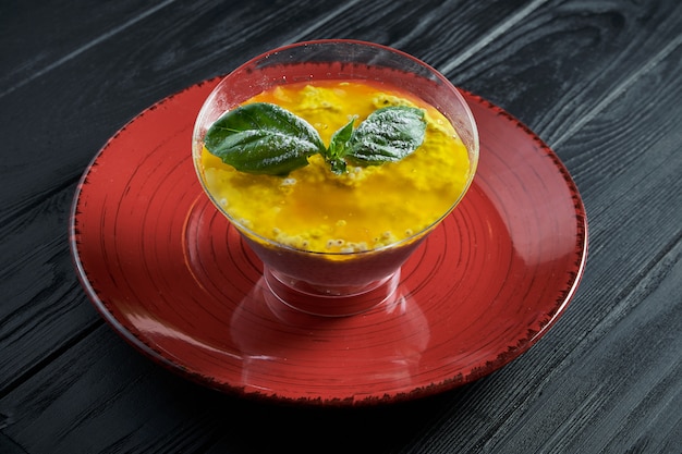 Savoureux pudding à la mangue fait maison avec des graines de chia dans un bol transparent sur un fond en bois noir. Copiez l'espace. Fermer