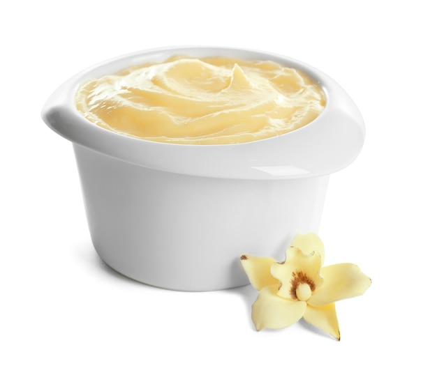 Photo savoureux pudding à la vanille dans un ramequin et une fleur sur fond blanc