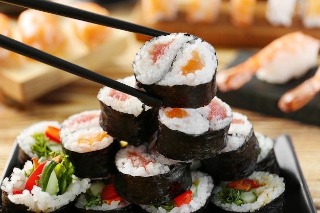 Savoureux rouleau de sushi avec gros plan de baguettes noires