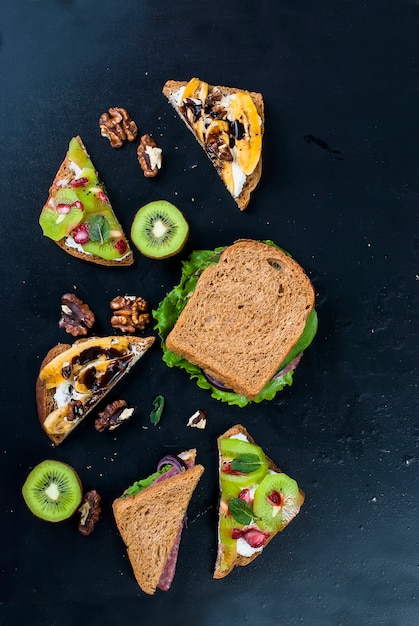 Savoureux sandwiches aux bananes, noix et chocolat, kiwi, fraises et menthe sur fond noir