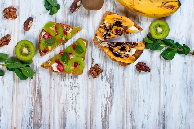 Savoureux sandwiches sucrés avec des bananes, des noix et du chocolat, sur une table en bois