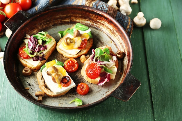 De savoureux sandwichs sur une vieille casserole sur une table en bois