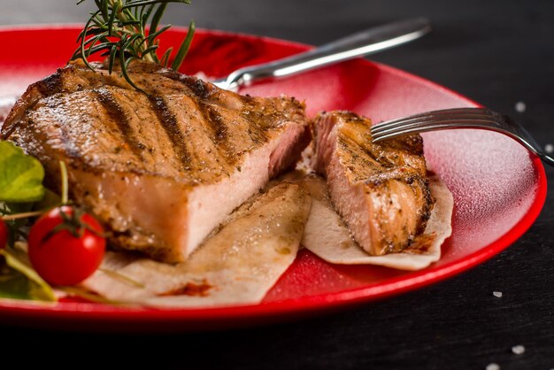 Photo savoureux steak de marbre grillé frais dans une assiette rouge