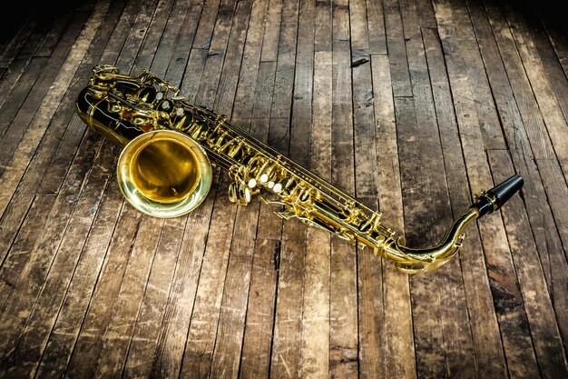 Le saxophone, un instrument de musique de jazz jaune, est posé sur une scène en bois brun.