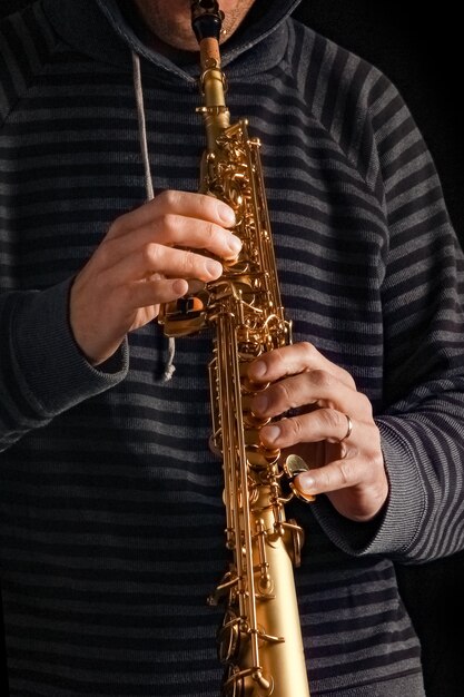 Saxophone soprano entre les mains d'un mec sur une surface noire