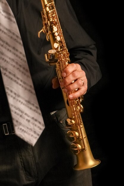 Saxophone soprano entre les mains d'un mec sur une surface noire