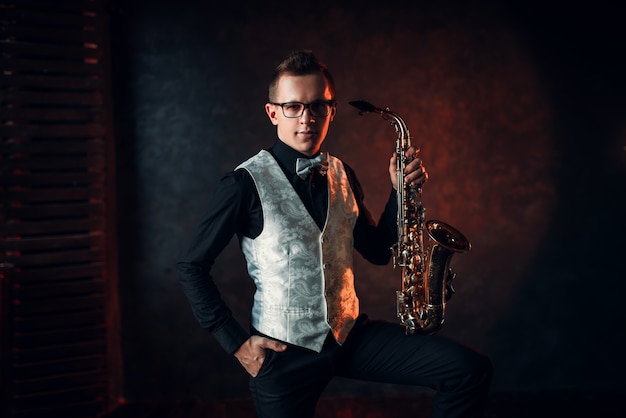 Saxophoniste masculin posant avec saxophone, homme de jazz.