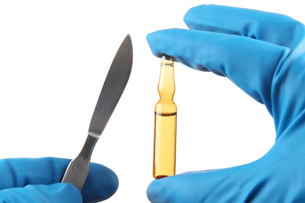 Scalpel médical et flacon pour injection dans les mains avec des gants bleus. traitement des malades