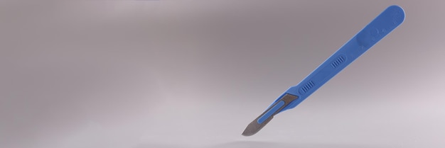 Scalpel médical avec manche bleu sur fond gris