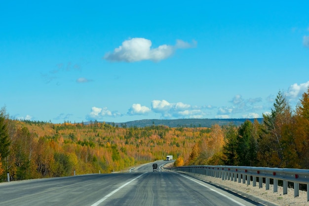 Scène d'automne lumineuse avec route parmi les arbres orange et verts et ciel bleu Mise au point sélective douce Beauté de la nature concept de voyage